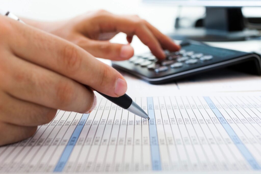 A close-up of a man using a calculator and a spreadsheet